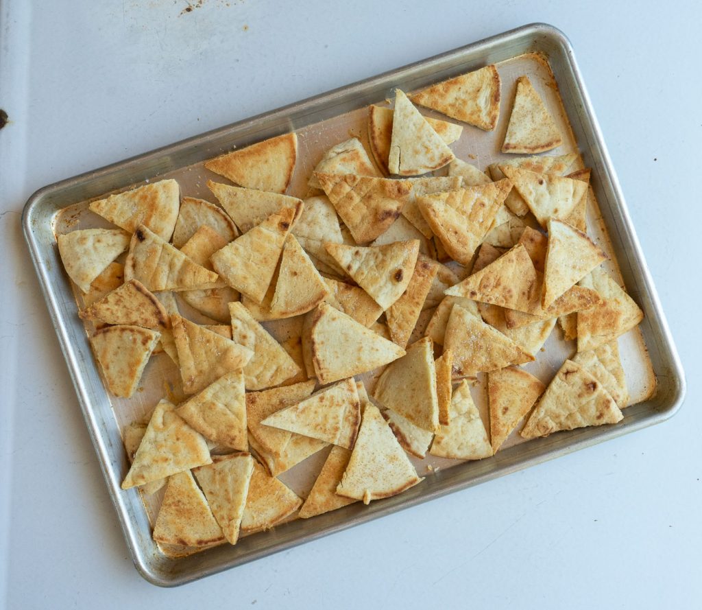 sheet pan sitting on a gray countertop with baked pita chips on the pan