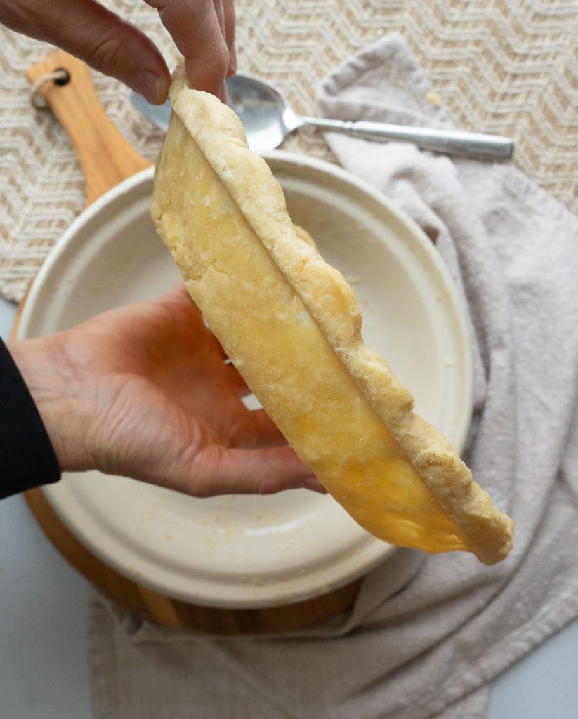 holding fully cooked pie crust above pie plate