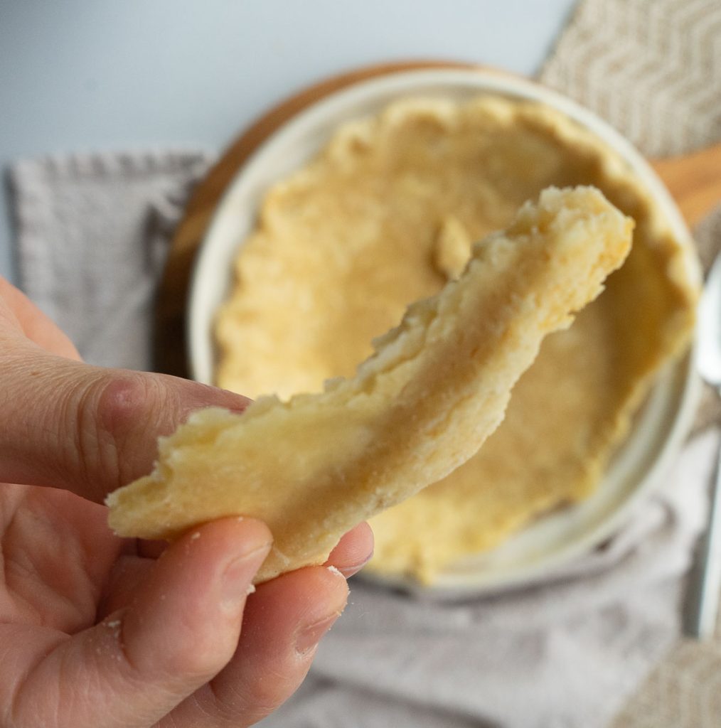 holing a piece of pie crust to show the flakiness of the crust