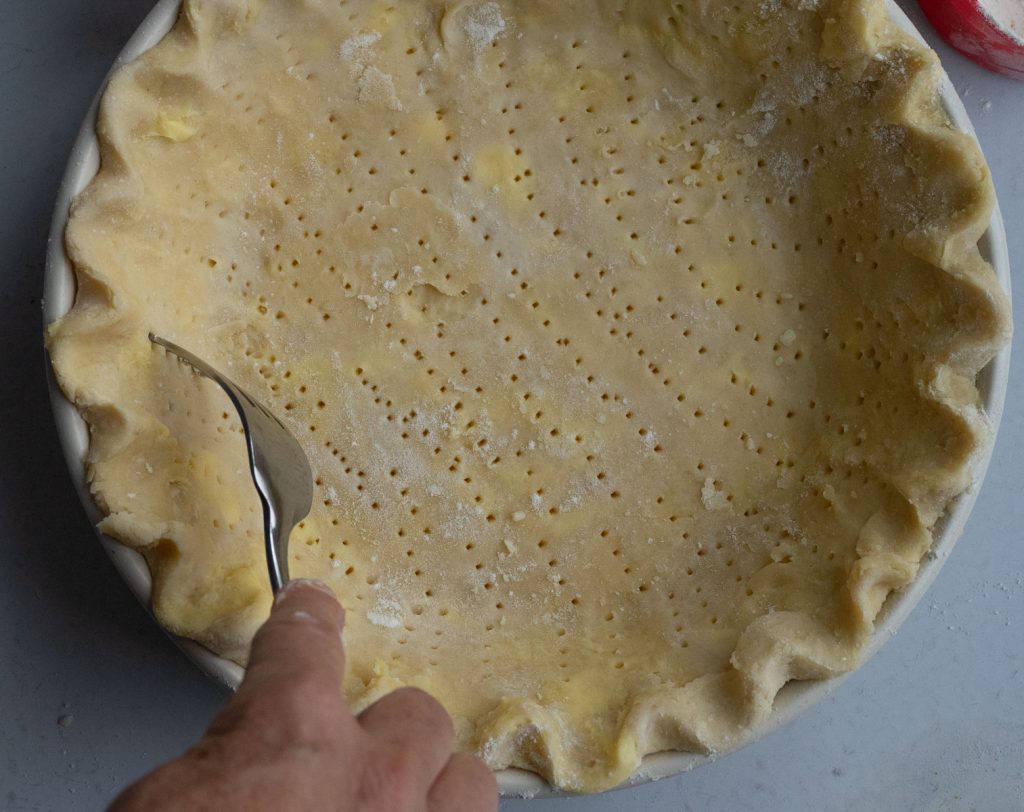 fork poking holes in the pie crust for blind baking pie crust 