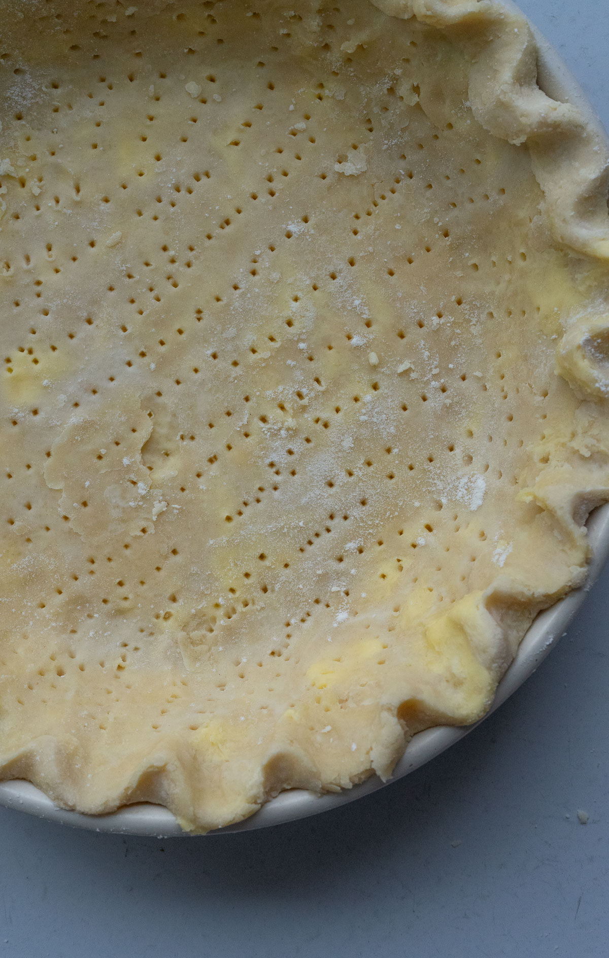 formed pie dough in a pi plate with crimped edges and fork holes poked in crust